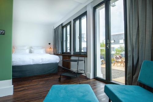 a bedroom with a bed and sliding glass doors at Bateau Libre Hotel in Bénodet