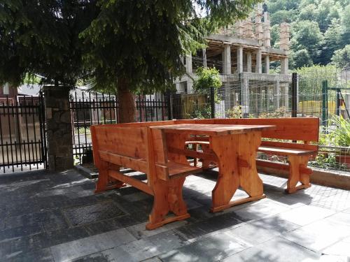 a wooden picnic table and bench in front of a fence at Pensiunea Memy in Buşteni