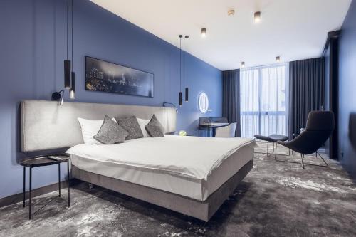 1 dormitorio con 1 cama grande y pared azul en Mamaison Residence Diana, en Varsovia