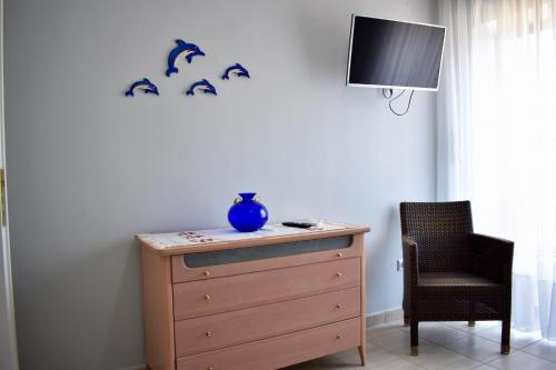 komodę z niebieską wazą na górze obok krzesła w obiekcie Alkyon Perea Apartments w mieście Perea