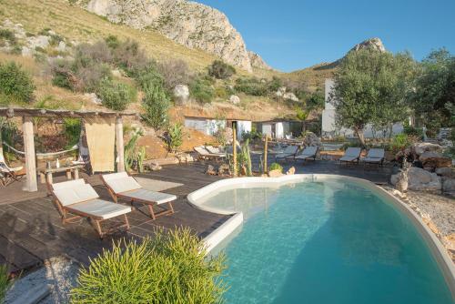 uma piscina com espreguiçadeiras e uma montanha em Naturarte Suites em Terrasini