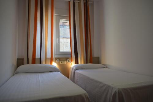 two beds in a room with a window at Apartamentos VIDA Finisterre in Finisterre