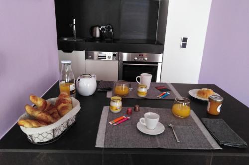 una mesa con una cesta de cruasanes y vasos de zumo de naranja en APPART AIX MAZARIN en Aix-en-Provence