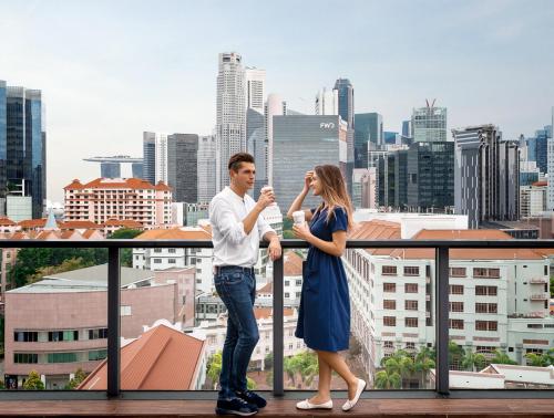 a man and a woman standing on a balcony in front of a city at Holiday Inn Express Singapore Clarke Quay by IHG in Singapore