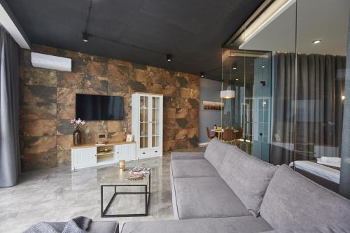 a living room with a couch and a tv on a stone wall at Gagarin Plaza Luxury Sea View Apartments in Odesa