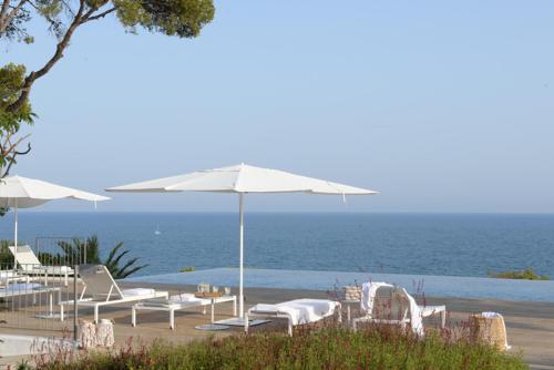 una playa con sillas y sombrillas y el océano en Villa Casa del Mar, en Sant Pere de Ribes