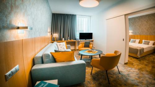 een hotelkamer met een bank, een bed en een tafel bij Hotel Aréna in Košice