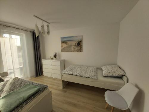 sypialnia z dwoma łóżkami i krzesłem w obiekcie Apartament Przy Lesie Słoneczne Tarasy w Dziwnówku