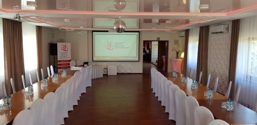 a conference room with white chairs and a screen at Route One - Restauracja & Pokoje Hotelowe in Zgierz