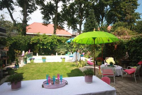 un tavolo con ombrellone verde in un cortile di De Pimpelmees a L'Aia