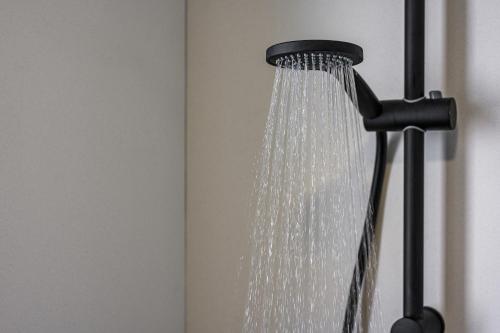 a shower head with water coming out of it at Aegean Breeze Luxury Apartments next to the sea in Maleme
