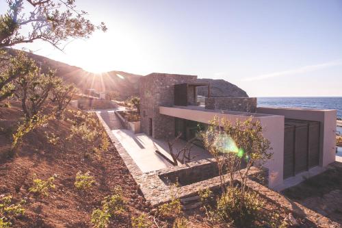 a house on a hill with the ocean in the background at Nuez Villas in Mochlos