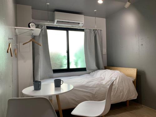 a small bedroom with a bed and a table and a window at Itos Ebisu in Tokyo