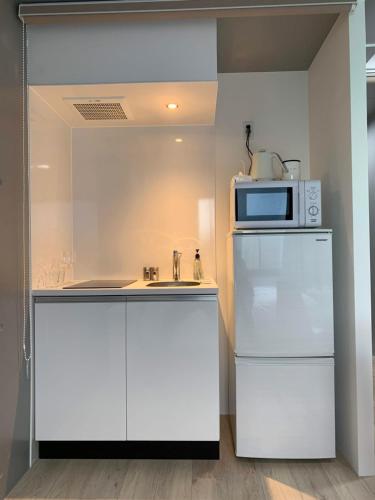 a kitchen with a white refrigerator and a microwave at Itos Ebisu in Tokyo