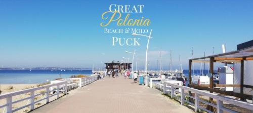 a pier with people walking on it next to the water at Great Polonia Beach & Molo in Puck