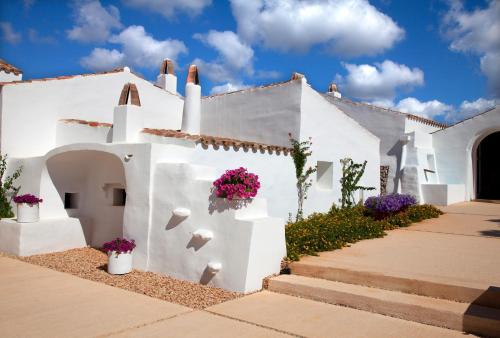 une maison blanche avec des fleurs sur son côté dans l'établissement Torralbenc, a Small Luxury Hotel of the World, à Cala'n Porter