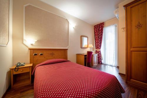 a bedroom with a bed with a red comforter at Hotel Elena in Saint Vincent