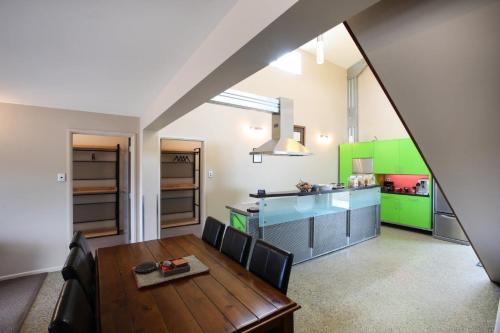 una cocina con mesa y una cocina con armarios verdes en Tussock Lodge - Waipiata, en Waipiata