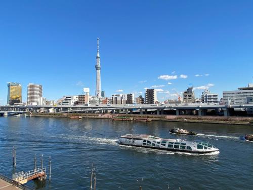 a boat on a river with a city in the background at Feel Asakusa Stay in Tokyo