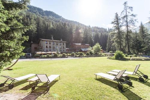 un groupe de bancs dans un champ avec un bâtiment dans l'établissement Chalet Eden Eco Hotel, Restaurant & Wellness, à La Thuile