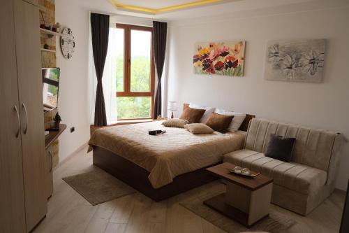 um quarto com uma cama, um sofá e uma janela em Apartman D&V Milmari Resort S10 em Kopaonik