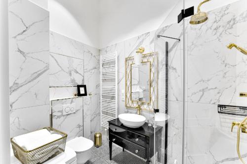 Łazienka z marmurowymi ścianami, umywalką i lustrem w obiekcie Apartament Golden Place w Krakowie