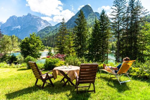 a woman sitting in chairs at a table in the grass at House Moose't Getaway, Kranjska Gora in Kranjska Gora