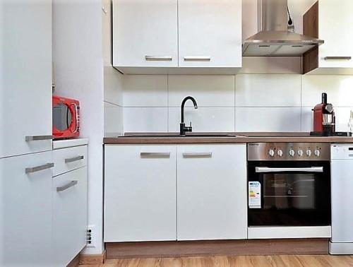 a kitchen with white cabinets and a sink and a stove at Riesling - helle und großzügige Wohnung mit guter Anbindung in Mainz