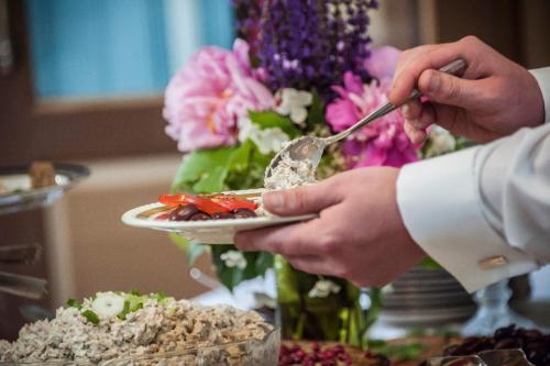 een persoon houdt een bord vast met voedsel erop bij Löydön Kartano Camping in Mikkeli
