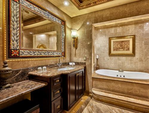 a bathroom with a tub and a large mirror at Peermont D'oreale Grande at Emperors Palace in Kempton Park