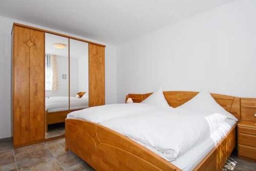1 dormitorio con 1 cama grande y espejo en Ferienhaus Nordwind en Bensersiel