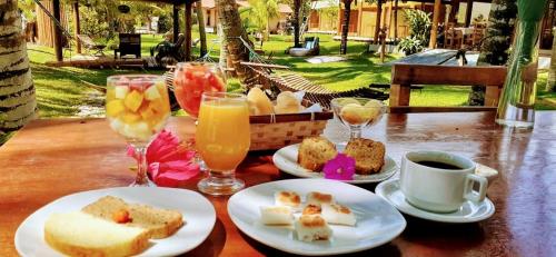 a table with plates of food and glasses of drinks at Pousada Areia Preta in Cumuruxatiba