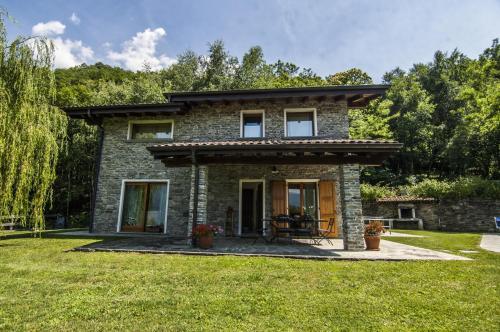 a stone house with a table in a yard at Villa Betulla con piscina privata sul lago di Como in Colico