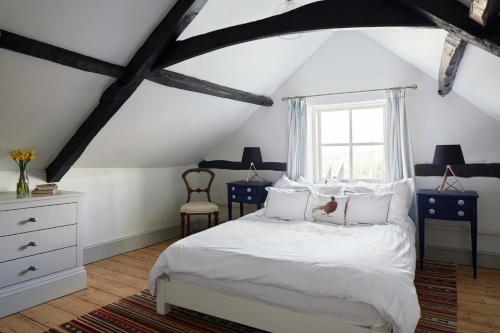 a bedroom with a white bed and a window at Dog Cottage in Little Barningham