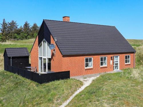 a red brick house with a black roof on a hill at 8 person holiday home in Hanstholm in Vigsø