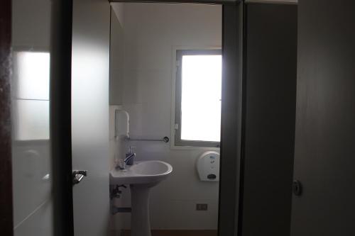 a white bathroom with a sink and a window at Albergue Turístico Silleda in Silleda