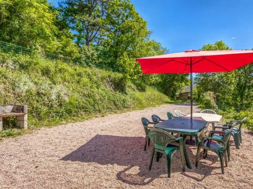 une table et des chaises avec un parapluie rouge dans l'établissement Lovely Cottage in Pontgibaud with Garden near Lake, à Pontgibaud