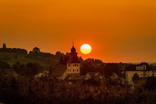 a sunset over a town with a clock tower at Sali Homes - GaesteHaus Lamm Obersulm in Obersulm