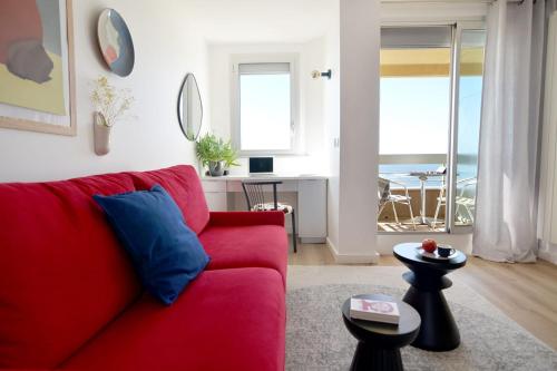 un salon avec un canapé rouge et une table dans l'établissement NOUVELLE VAGUE Modern Ocean View STUDIO w balcony - Swimming Pool, à Biarritz