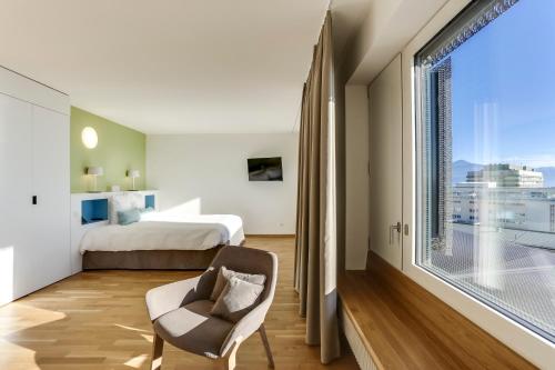 sypialnia z łóżkiem i dużym oknem w obiekcie Hôtel des Patients w Lozannie