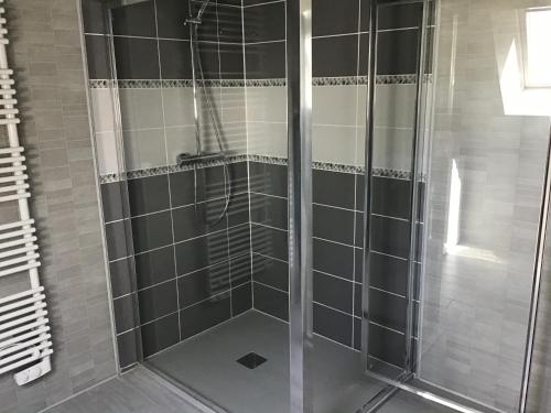 um chuveiro com portas de vidro na casa de banho em chez diane em Barbeville