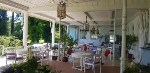 eine Veranda mit Tischen, Stühlen und einem Kronleuchter in der Unterkunft Golfhotel Kaiserin Elisabeth in Feldafing