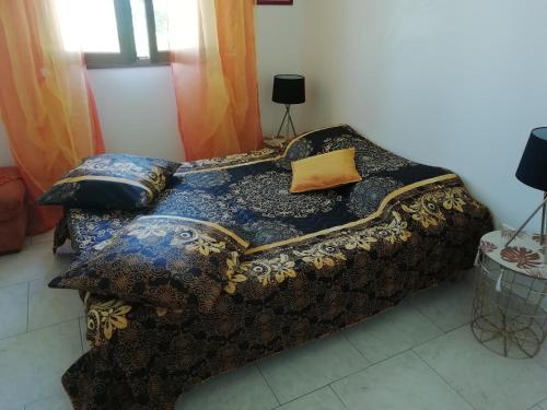ein Bett mit einer Decke und Kissen darauf in der Unterkunft Gîte le pastel in Puéchoursi