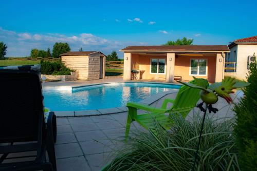 une piscine avec une chaise verte et une maison dans l'établissement Gîte le pastel, à Puéchoursi