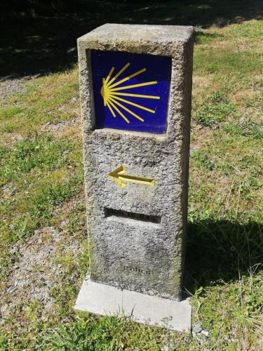 a stone box with a sun on it in the grass at Albergue Camiño Real in Sigüeiro