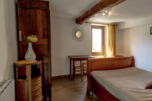 ein Schlafzimmer mit einem Bett und einem Tisch mit einer Vase in der Unterkunft Gîte Chambres d'hôtes Le Bellevue in Montbrun-les-Bains