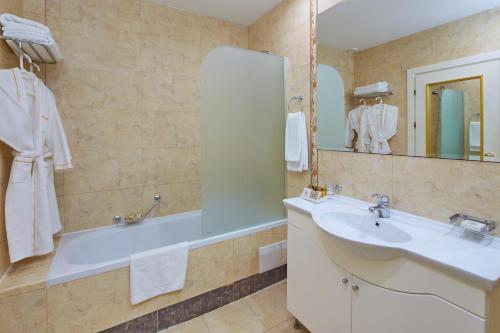 a bathroom with a tub and a sink and a mirror at Planeta Hotel & Aquapark - Ultra All Inclusive in Sunny Beach