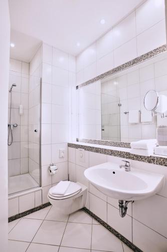 a white bathroom with a sink and a toilet at Lounge-Hotel Seeterrassen in Wandlitz