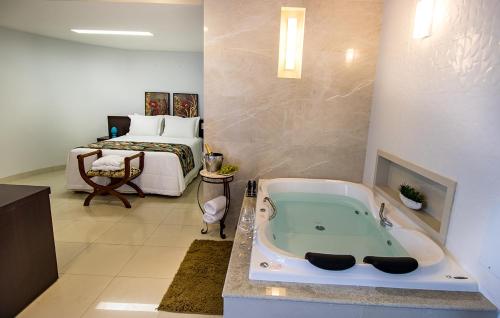 a bathroom with a bath tub in front of a bed at Residence Hotel Imperatriz in Imperatriz