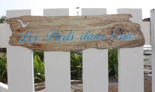 a wooden sign on a white fence at Villa les Pieds dans l'Eau in Trégastel